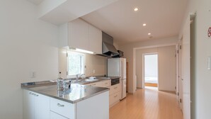 A modern kitchen with white cabinetry, stainless steel countertops, and a central island. - Sakura (Kutchan)