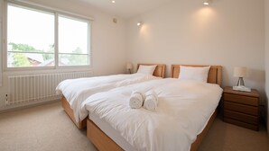 A bedroom with a large bed, two bedside tables, and a window. - Sakura (Kutchan)