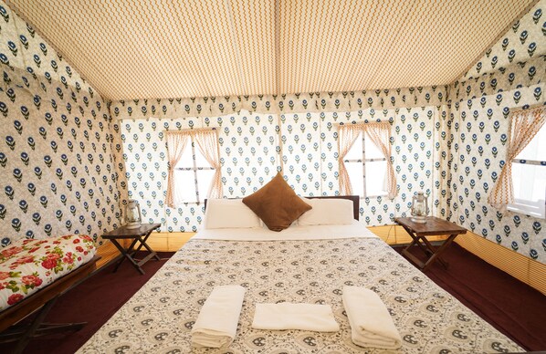 Quarto com cama grande, duas mesas de cabeceira, janela com cortinas e papel de parede estampado.
