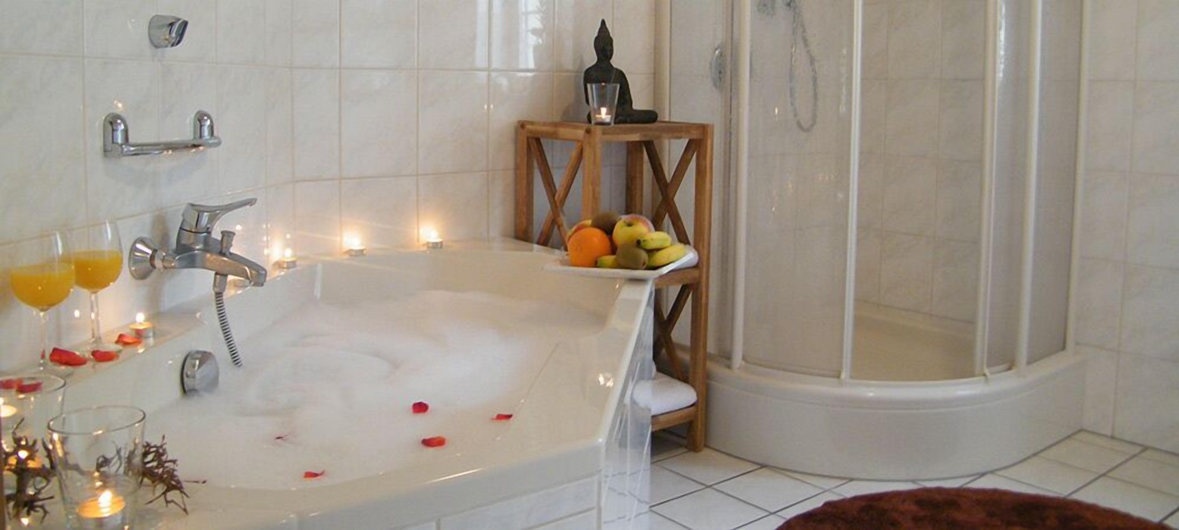 Ein Badezimmer mit Badewanne, Dusche und einem hölzernen Hocker mit Obst.