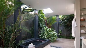Une salle de bain moderne avec une baignoire sur pieds, une végétation luxuriante et une douche à parois de verre.