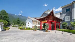 A traditional building with a red roof and white walls, surrounded by a paved courtyard and greenery. - Floral Hotel Dali Zhonghefang (Dali)