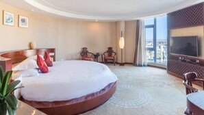 A hotel room with a large bed, a TV, a desk, and a view of the city. - Floral Hotel Dali Zhonghefang (Dali)