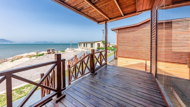 A wooden deck with a view of the sea and a beach. - Floral Hotel Qingdao Shark Stone (Qingdao)