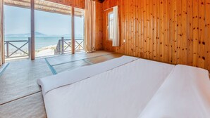 A wooden room with a bed, a window, and a view of the beach. - Floral Hotel Qingdao Shark Stone (Qingdao)