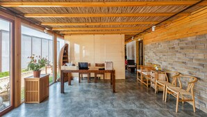 A modern interior with a wooden ceiling, a brick wall, and a dining area with wooden furniture. - Floral Hotel Qingdao Shark Stone (Qingdao)