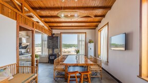 A spacious dining area with a long wooden table and chairs, a sofa, and a television on the wall. - Floral Hotel Qingdao Shark Stone (Qingdao)