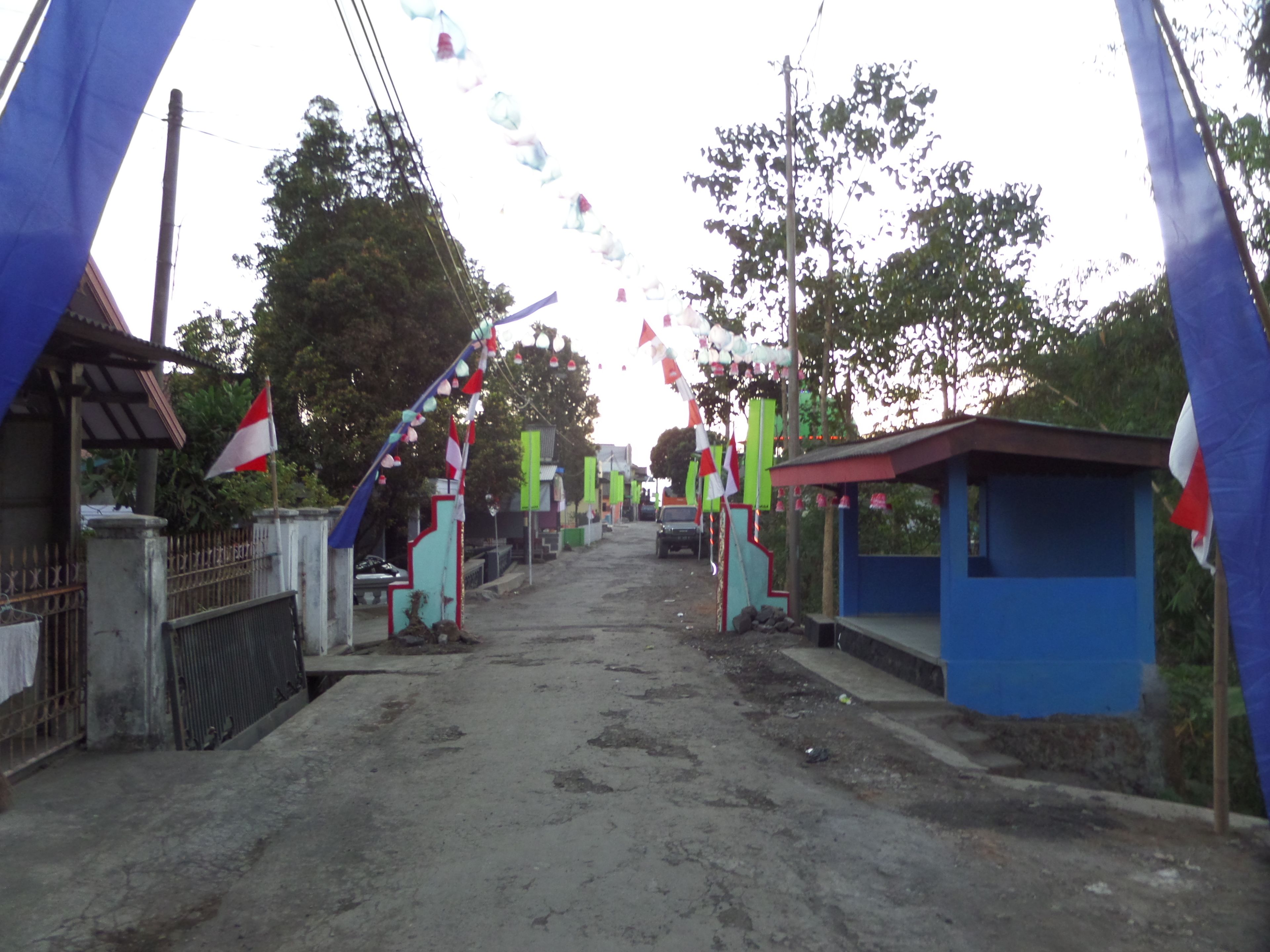 A street with a gate, a small blue building, and a flag.