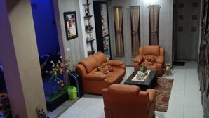 Uma sala de estar com dois sofás de couro marrom, uma mesa de centro e um tapete pequeno. À esquerda, há um aquário com decorações coloridas.