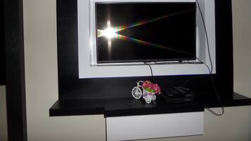 A television mounted on a black and white wall, with a small decorative item below it.