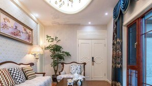 A room with a sofa, a small table, a potted plant, and a door with a decorative curtain. - Floral Hotel Enshi Xiaoxihu Yihao (Enshi)