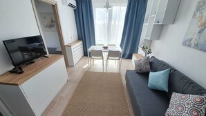 Een moderne woonkamer met een televisie, bank en een eethoek.