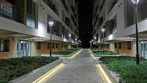 Een nachtzicht van een modern appartementencomplex met een centrale gangpad, verlicht door lantaarns.