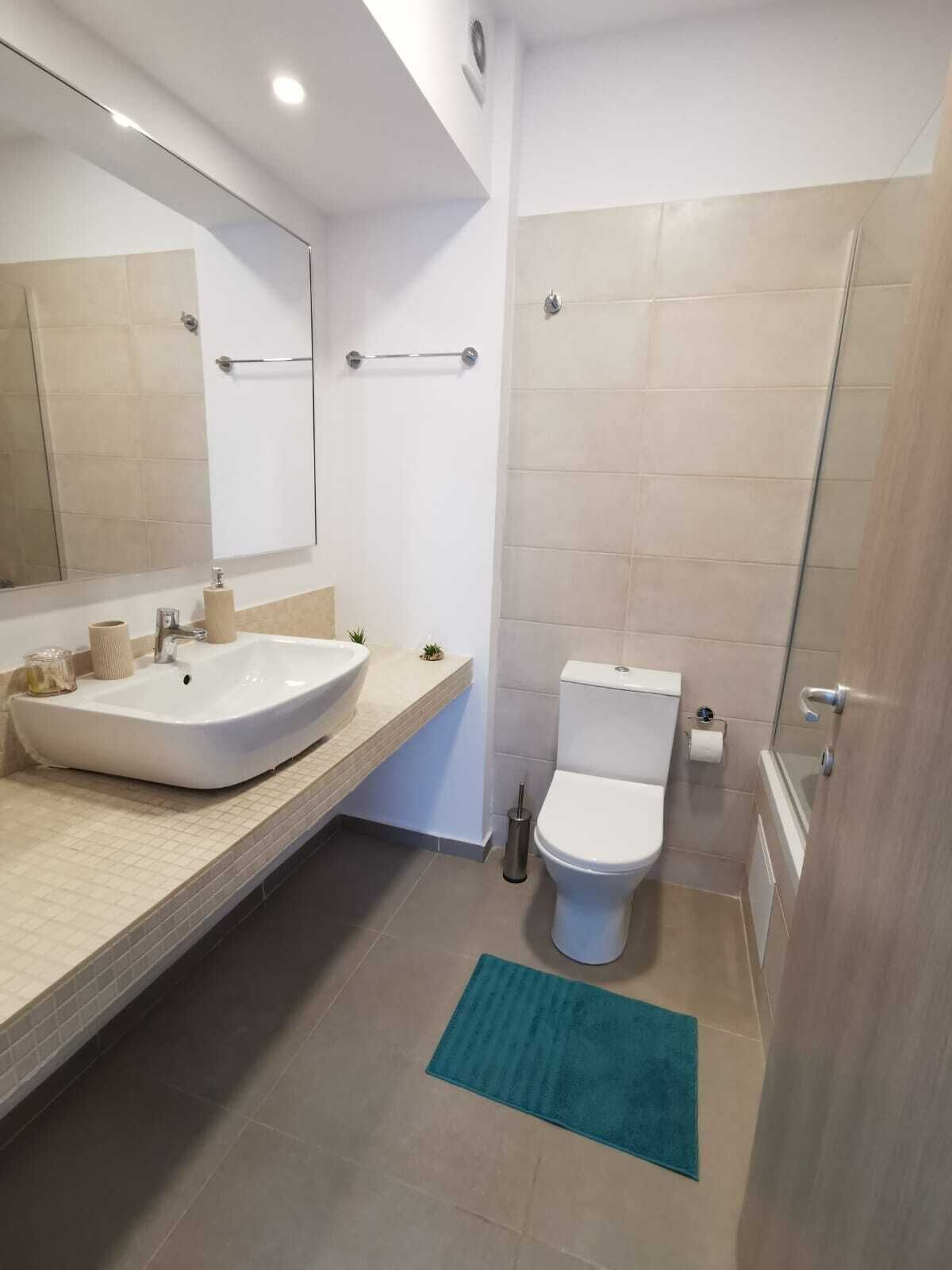 A modern bathroom with a large sink, toilet, and shower area.