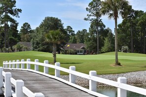 Stroll across the picturesque bridge to the clubhouse, surrounded by lush greenery and manicured lawns.