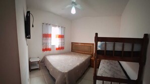A bedroom with a single bed, a wooden bunk bed, a ceiling fan, and a nightstand.