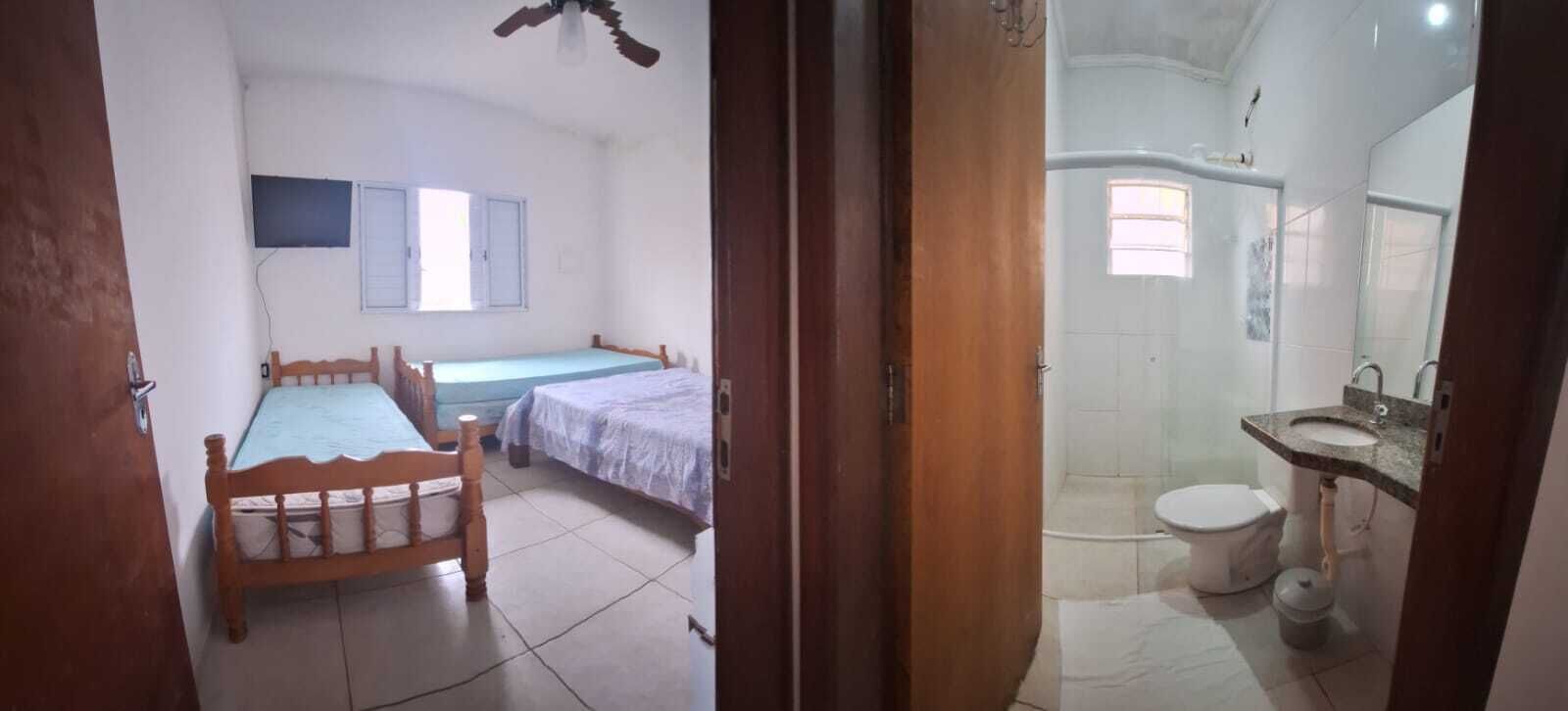 Una camera con due letti, un ventilatore a soffitto e un bagno con il water e il lavandino.