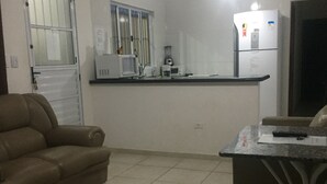A compact living space with a kitchenette, a sofa, and a dining table.