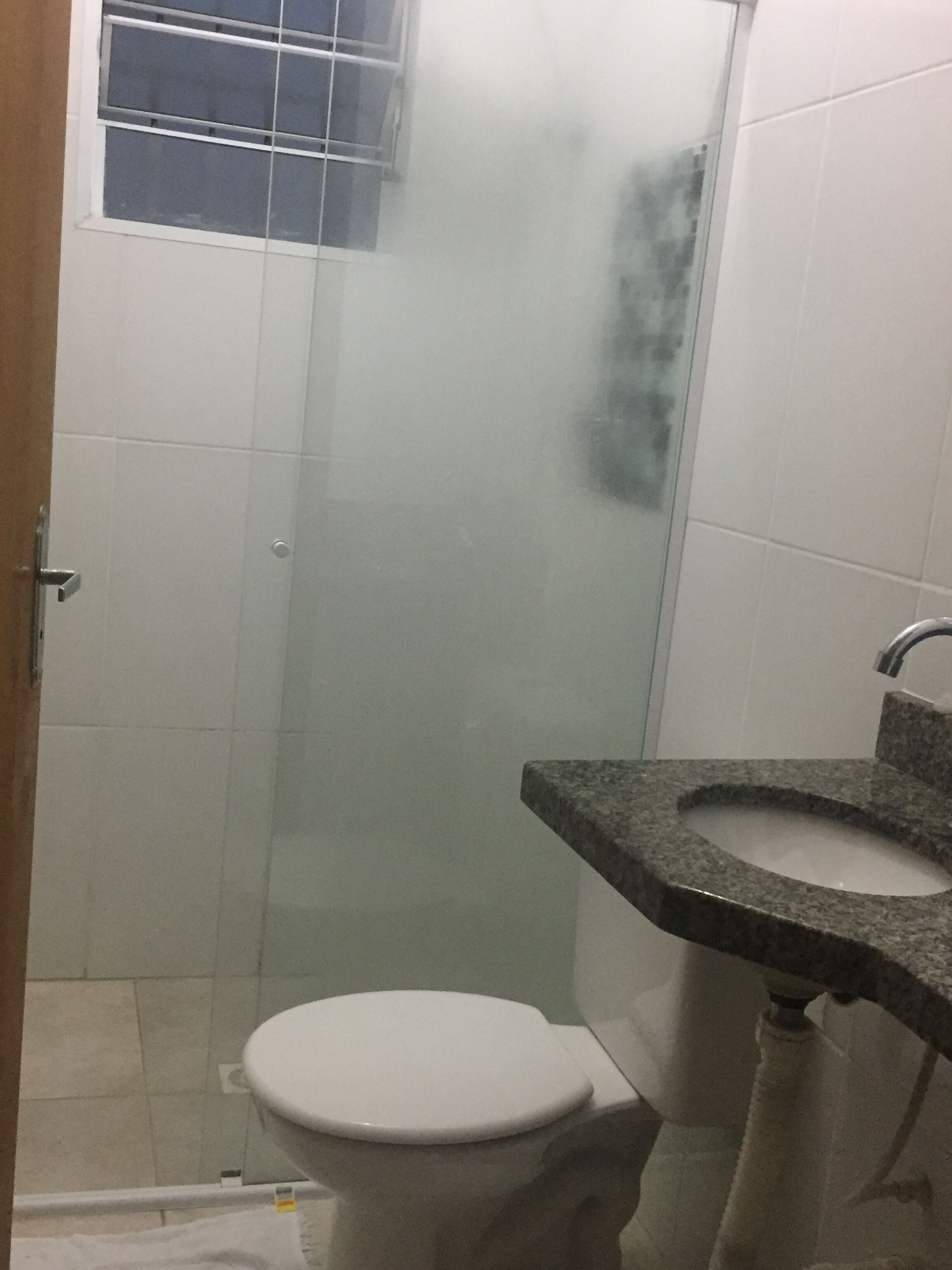 Une salle de bain avec des toilettes blanches, une douche en verre et un lavabo en granit.