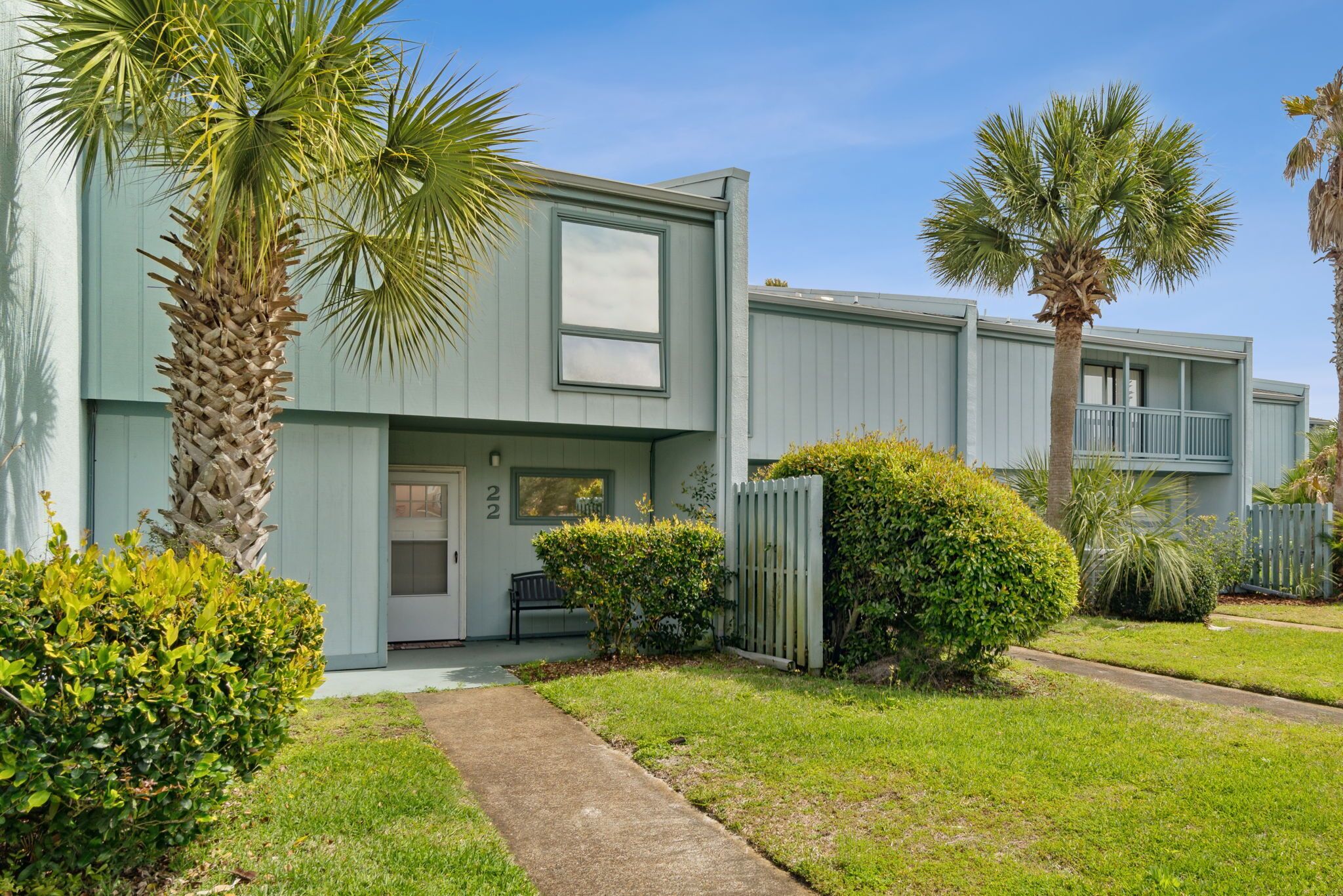 A modern apartment building with a flat roof, large windows, and a well-maintained lawn.