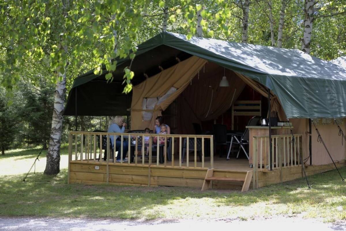 A rustic wooden cabin with a porch, a grill, and a covered seating area.