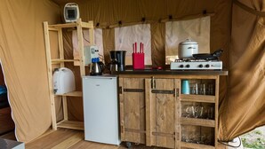 Een kleine keuken met een koelkast, fornuis en diverse kookgerei.