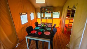 Een eetruimte met een tafel voor vier personen, omgeven door oranje gordijnen en houten vloeren.