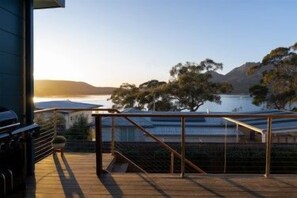 A wooden deck with a metal railing overlooking a body of water and trees.