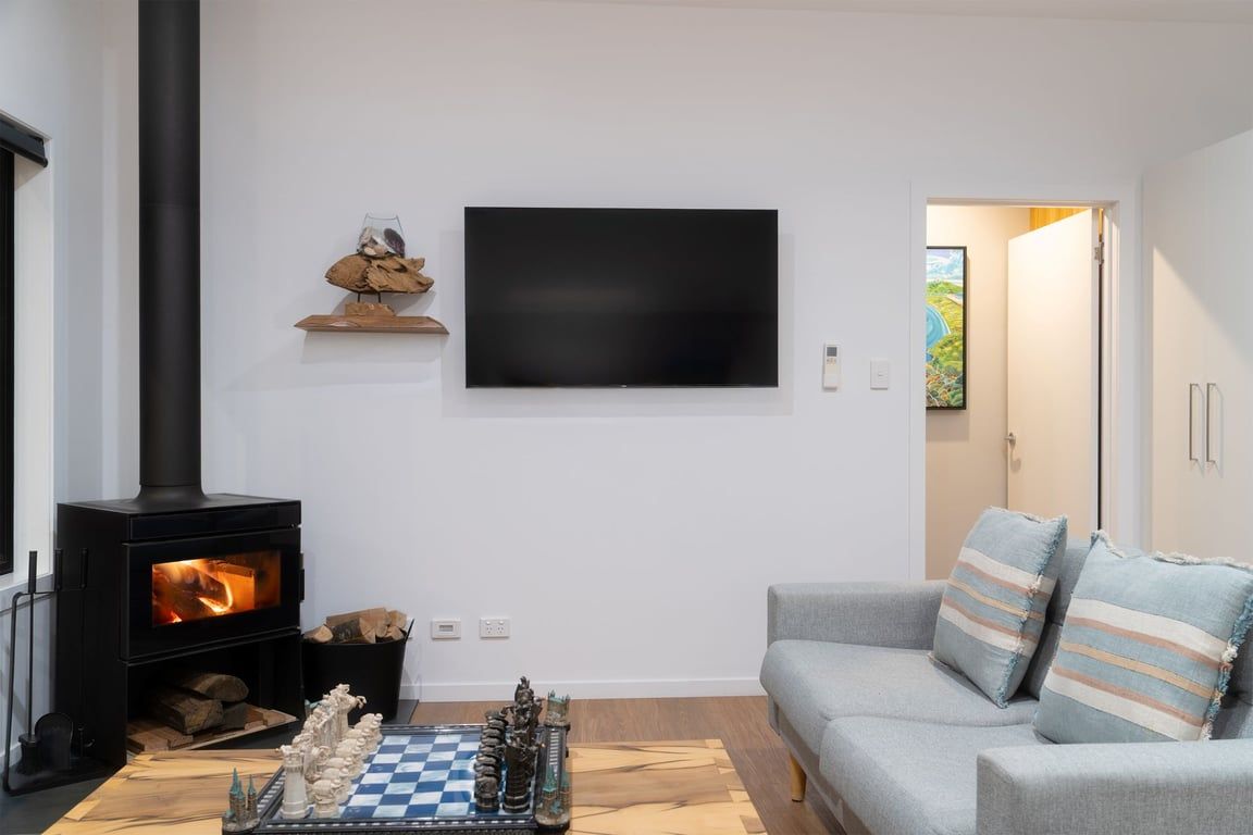 A living room with a fireplace, a flat-screen TV, a chessboard, and a sofa.