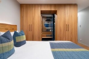A bedroom with a bed, a wooden wardrobe, and a small closet.