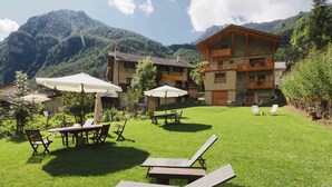Un patio de hotel con mesas al aire libre, un paisaje de montañas y un edificio de madera con balcones.