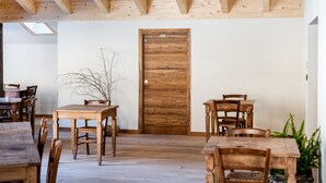 Un comedor con mesas y sillas de madera, una puerta de madera y una planta.