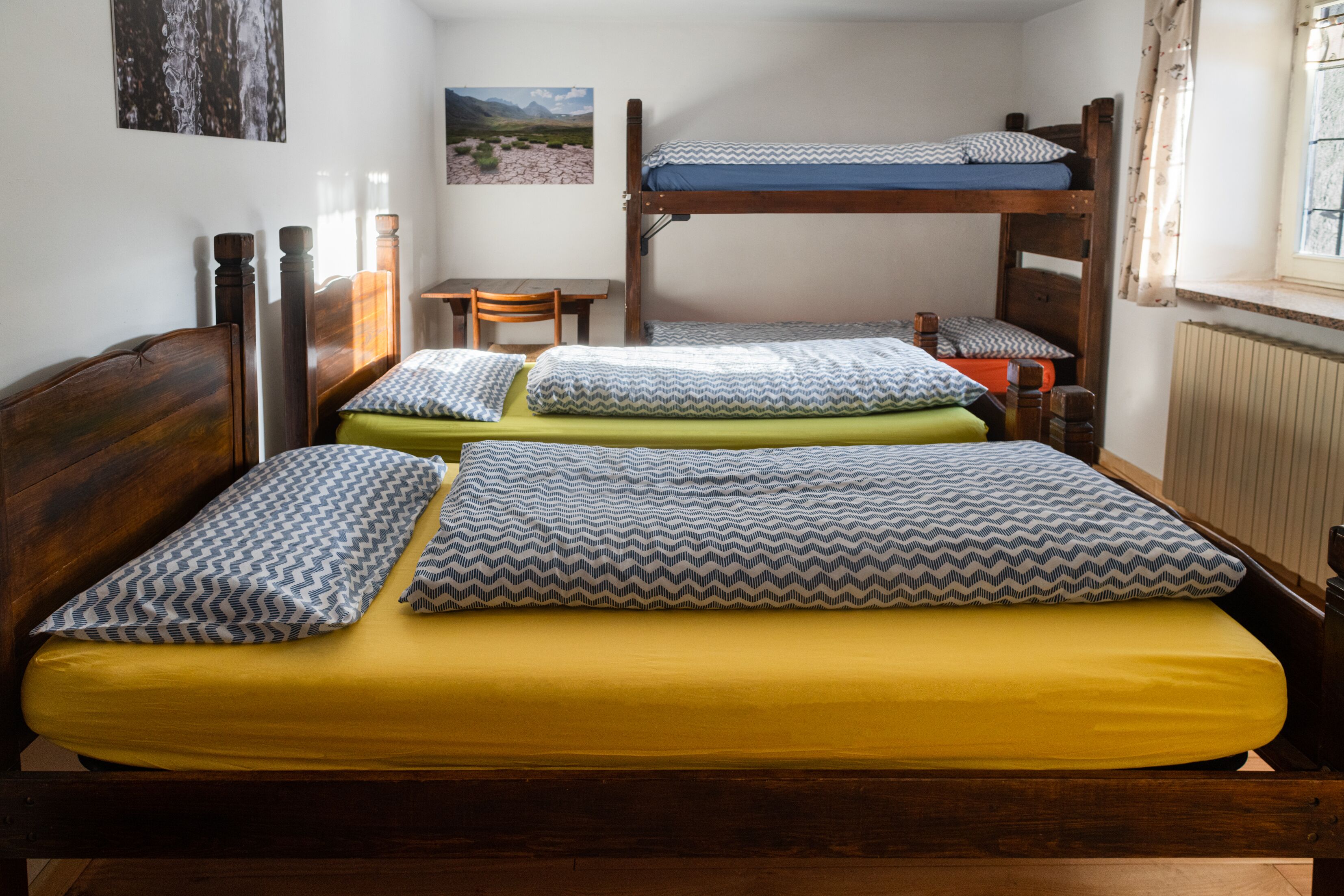 A dormitory room with bunk beds, a desk, and a chair.