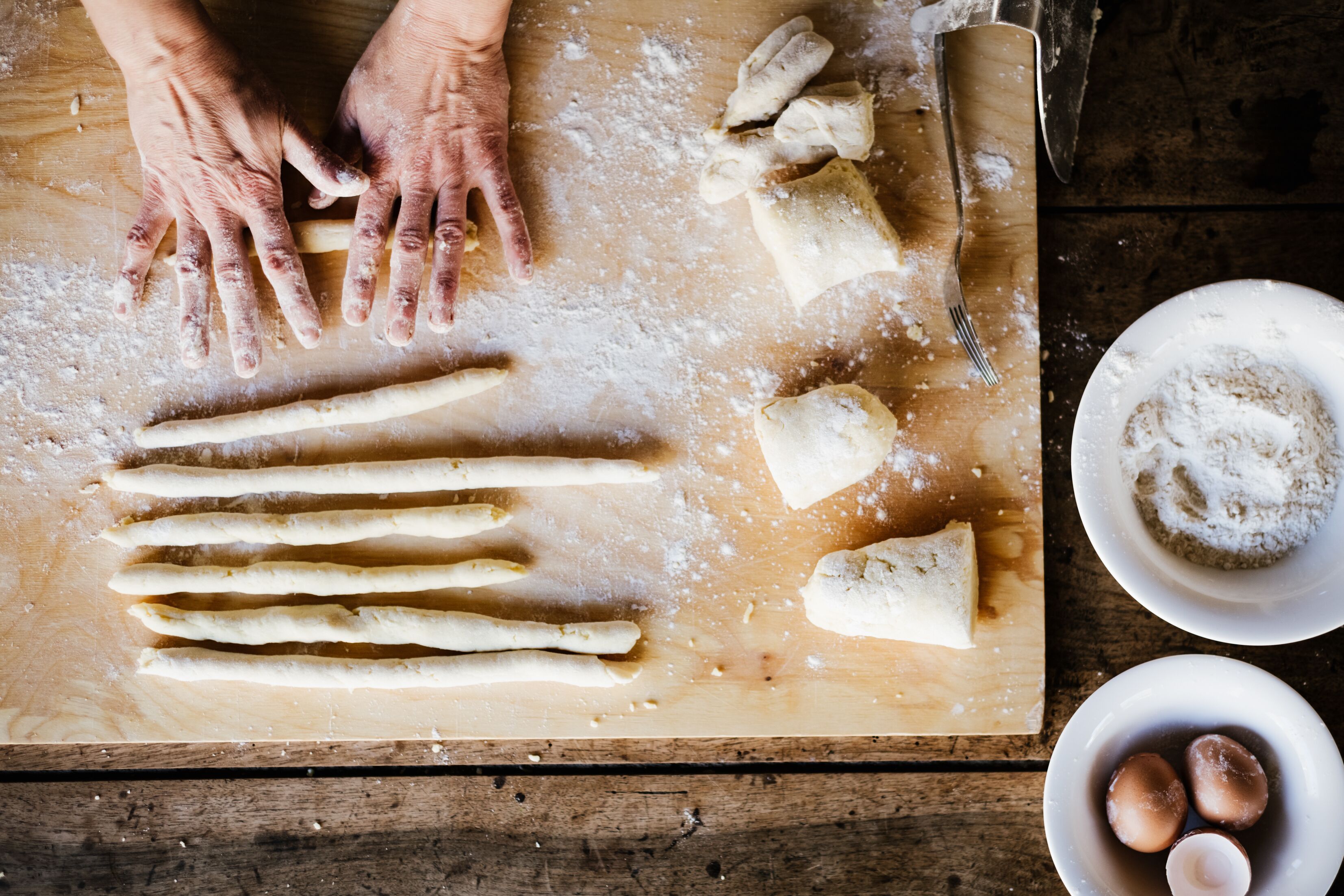 Una mesa de madera con masa, un cuchillo y un plato con un pastel.