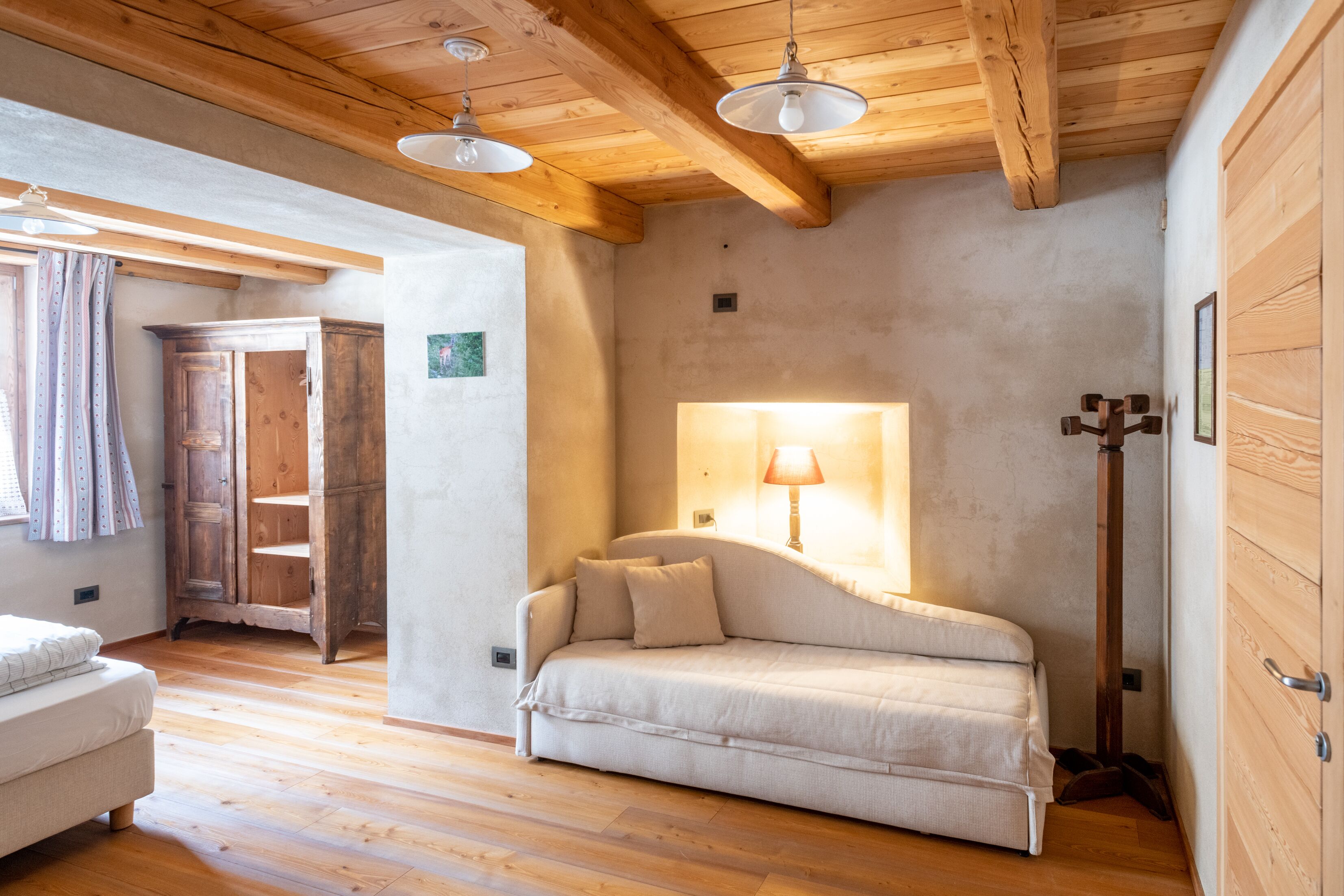 A cozy room with a sofa, wooden floor, and a lamp.