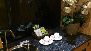 Un baño de hotel con un lavabo, una orquídea en maceta y artículos de aseo en la encimera.