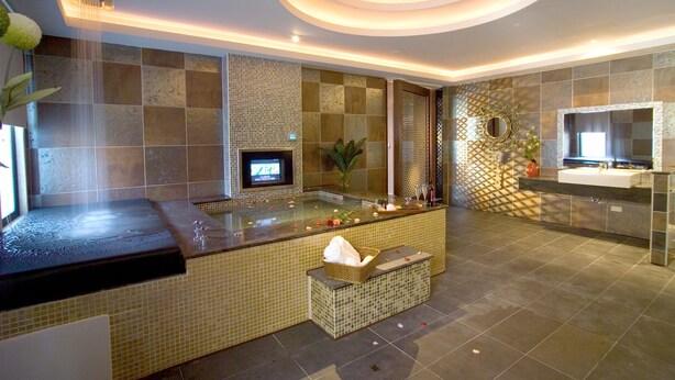 Un baño moderno con una bañera grande, un tocador con espejo y una pantalla de televisión.