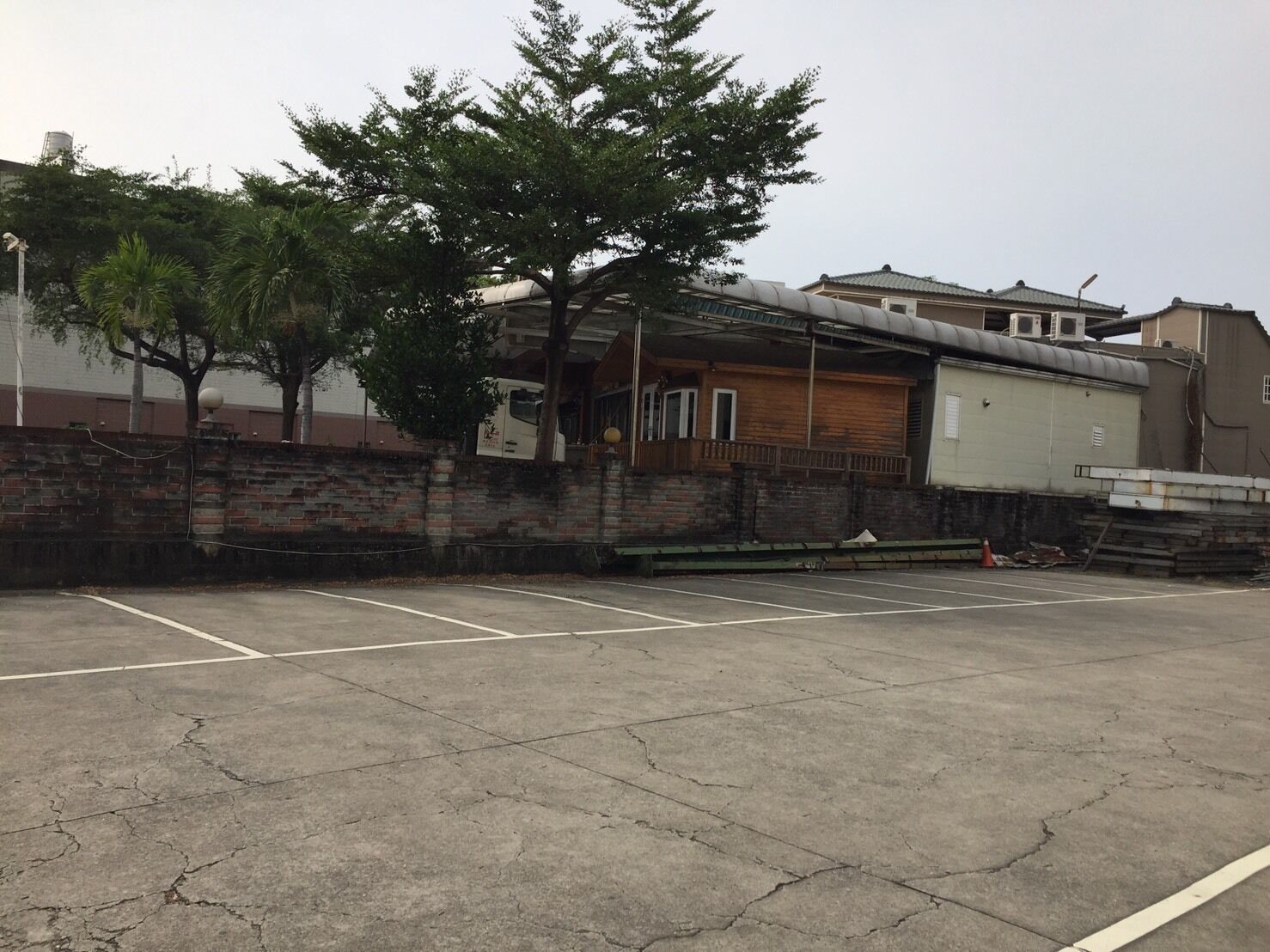A parking lot with a building that has a brick wall and a wooden structure.