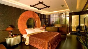 Una habitación de hotel moderna con una cama grande, un espejo redondo, techo de madera y vistas al exterior con vegetación.