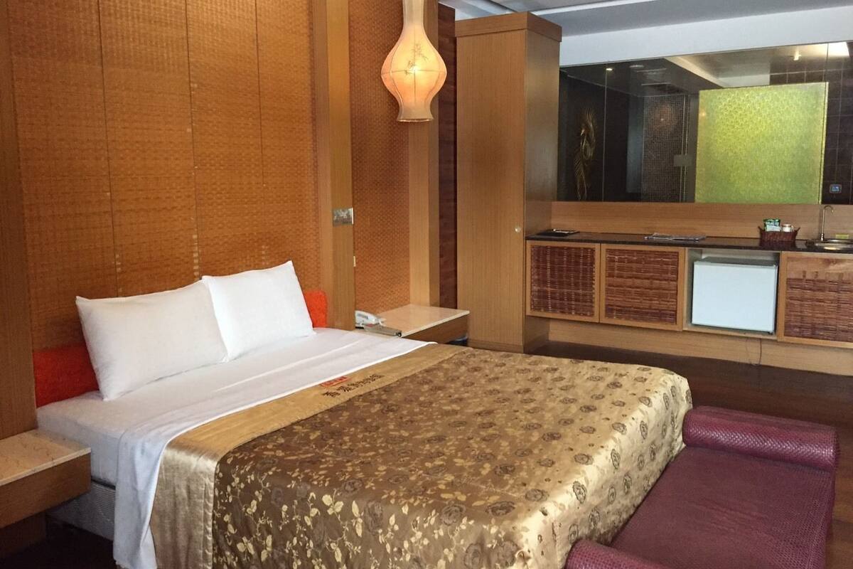 Habitación de hotel con cama, escritorio, espejo y minibar.