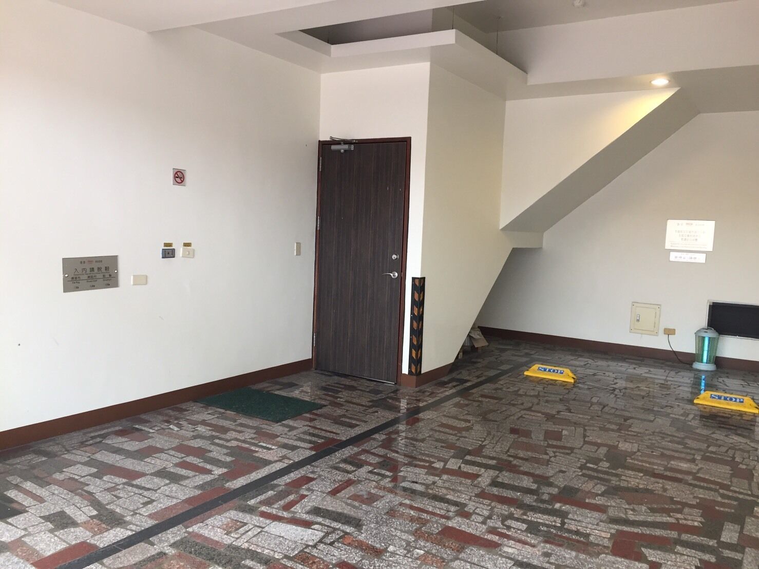 A hallway with patterned flooring, a closed door, and a staircase.