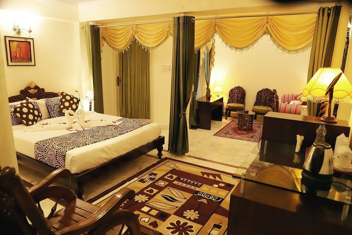 A hotel room with a bed, a desk, a chair, a sofa, and curtains.