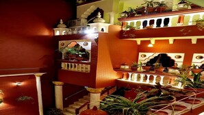 A model of a traditional Indian palace with multiple levels, balconies, and a variety of potted plants. - Ganesha Palace (Amritsar)