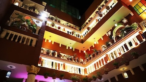 A multi-level atrium with balconies adorned with potted plants and warm lighting. - Ganesha Palace (Amritsar)