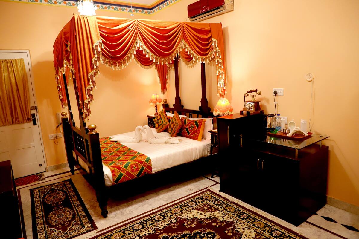 A four-poster bed with a canopy, a bedside table with a lamp, a dresser, and a rug.