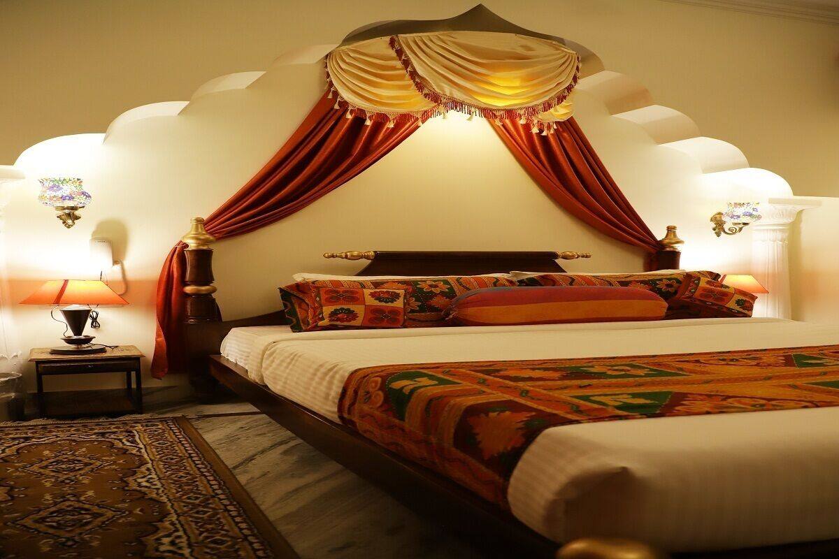 A four-poster bed with a canopy, two bedside lamps, and a patterned rug.
