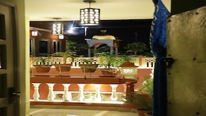 An outdoor area with a tiled floor, potted plants, and a decorative railing. - Ganesha Palace (Amritsar)