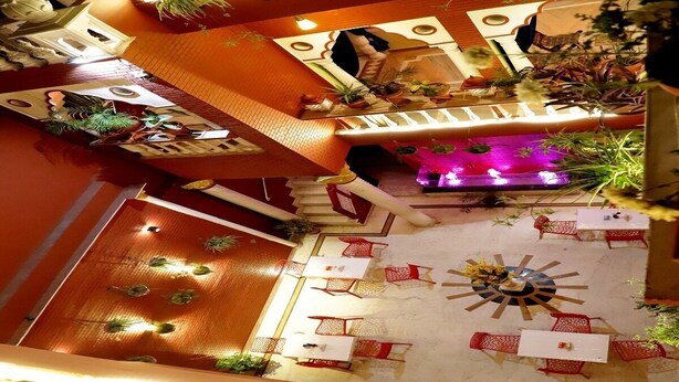 An indoor atrium with a central fountain, multiple seating areas, and decorative plants. - Ganesha Palace (Amritsar)