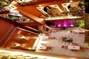 Un atrio interior con una fuente central, varias zonas de estar y plantas decorativas.