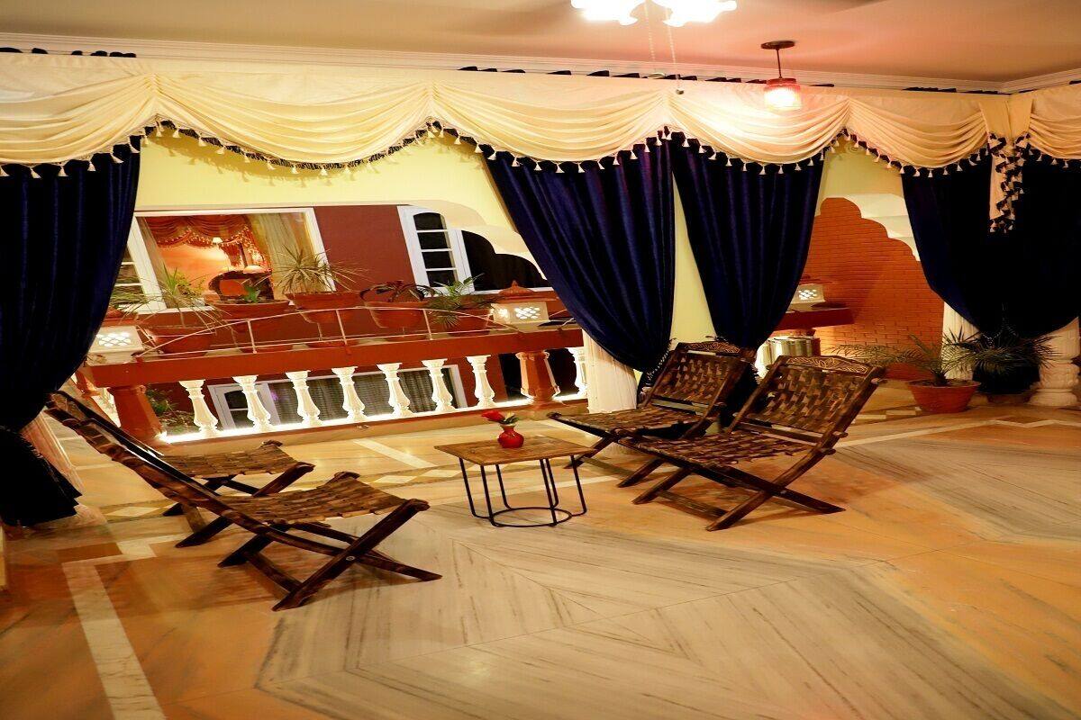 A room with a bar area, cushioned seating, and potted plants.